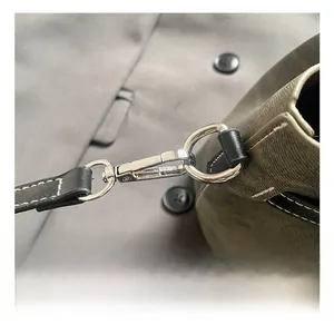Close-up of silver metal hook with white stitching detail on a green textured bucket bag