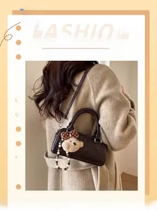 Detail of dark brown vintage Boston bag with plush bear charm and adjustable strap