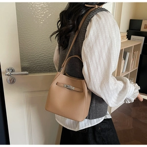 Detail of camel lychee leather bucket bag showing the metal twist lock and handle