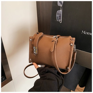 Close-up of brown litchi pattern leather texture and metal rivets on the handbag