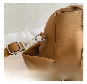Close-up of silver metal hooks and stitching details on a brown leather tote bag