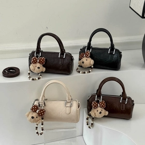 Detail of four colorful Boston cylinder bags with teddy bear charms on display