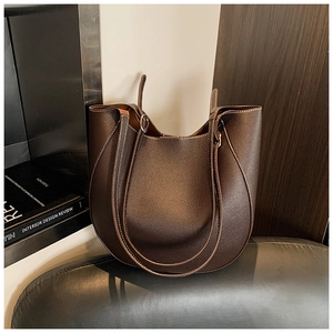 Primo piano della borsa tote marrone caffè in pelle martellata con base curva su uno sgabello