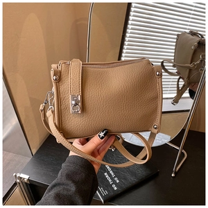 Detail of khaki pebbled leather shoulder bag featuring silver twist lock and rivets