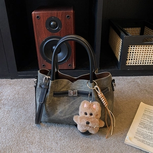 Close-up of vintage canvas tote bag with leather straps and plush puppy pendant