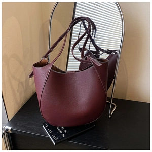 Dettaglio della borsa tote in pelle bordeaux con cuciture curve e tracolla sottile