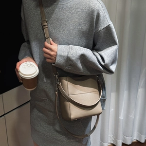 Khakifarbene Bucket Bag mit Litschimuster und Schultergurt am Model präsentiert