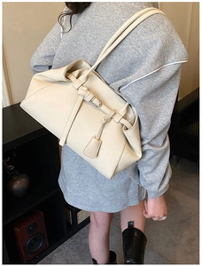 Close-up of beige lychee grain faux leather shoulder bag with silver buckle detail