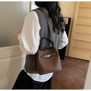 Close-up of brown pebbled leather bucket bag with classic turn-lock and leather straps