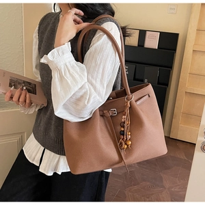 Brown leather tote bag with decorative tassel fringe shown in a lifestyle interior setting