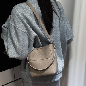 Detailansicht der Eimertasche aus genarbtem Leder mit Logo und abnehmbarem Gurt