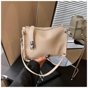 Close-up of beige lychee textured handbag with silver metal buckle and mirror reflection
