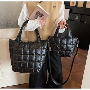 Dettaglio di due borse shopper trapuntate nere con manici in pelle in un contesto lifestyle