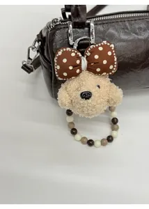 Plush puppy charm with polka dot bow and beaded ring on brown cylinder bag detail