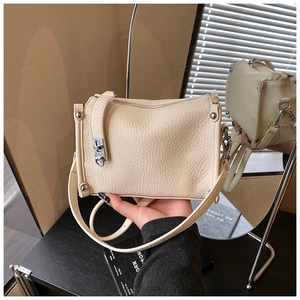 Detail of beige lychee leather Boston bag with silver locks and mirror reflection