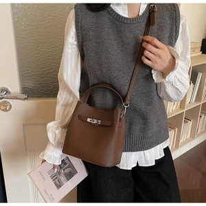 Detailed view of a brown pebbled leather bucket bag with silver clasp and shoulder strap