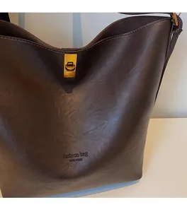 Detail of dark brown leather bucket bag with gold lock and textured vintage finish