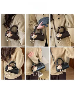 Detail view of glossy leather cylinder bag with plush bear charm in multiple angles