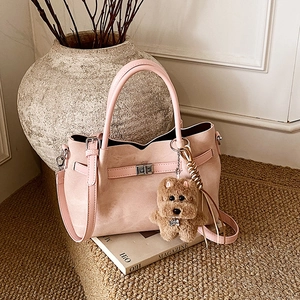 Detail of pink faux suede handbag with silver twist lock and plush dog charm