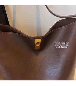 Detail of the golden metal twist lock closure on a dark brown textured leather bucket bag