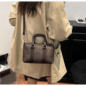 Detail of dark brown woven texture handbag shown styled with a crossbody leather strap