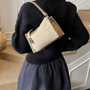 Close-up of beige leather Boston bag showing litchi texture and silver rivet details
