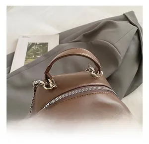Close-up of brown quilted leather bag with silver zipper and metal chain strap detail