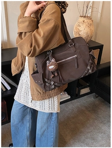 Detailed side view of dark brown tote bag with utility pockets and plush charm accessory