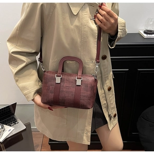 Detail of burgundy textured pillow bag showing silver buckles and handles on trench coat