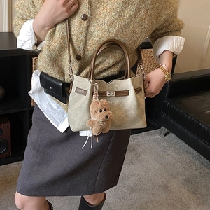 Detail of vintage tote bag showing canvas texture, leather handle, and metal lock