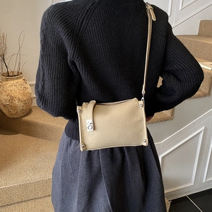 Detail of beige pebbled leather shoulder bag with silver hardware on a model