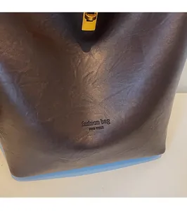 Detail of dark brown faux leather tote with textured finish and golden metal clasp lock