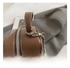 Detail of silver metal hook and quilted leather strap on a brown crossbody bag