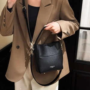 Detail der schwarzen Bucket Bag aus genarbtem Leder mit Tragegriff und abnehmbarem Gurt