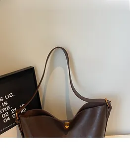 Close-up of a deep brown faux suede bucket bag with a golden metal twist lock and soft strap