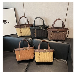 Collection of pleated tote bags in five colors displayed on a black leather sofa