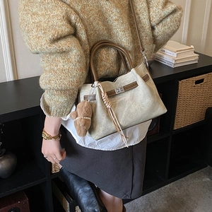 Detail of canvas tote bag with brown leather handles and silver metal turnlock