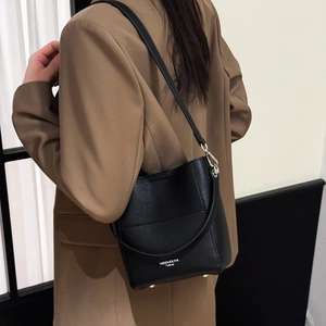 Schwarze Eimer-Handtasche aus Leder mit Narbenstruktur und silberner Aufschrift am Model
