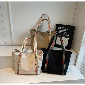 Detailed view of canvas tote bags with colorful floral embroidery on wide straps