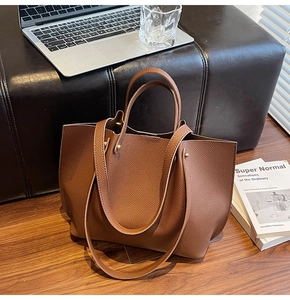 Detail shot of a dark brown pebble leather tote bag in a professional office setting