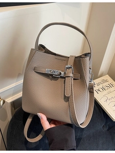 Minimalist beige lychee grain leather bucket bag with silver metal twist lock and strap
