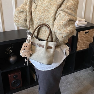 Detail of retro shoulder bag with leather handles and a cute brown bear charm accessory