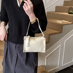 Detail of beige Boston bag with lychee leather texture and silver rivet decorations