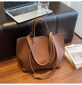 Detail of brown pebble leather tote bag with double handles in a professional workspace