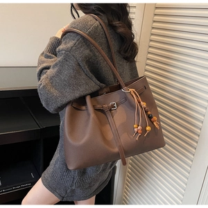 Detail of coffee brown matte leather tote bag with decorative strap and ethnic beaded charm