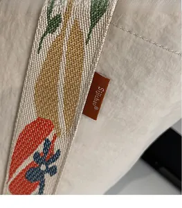Close-up of jacquard woven strap and leather logo patch on beige nylon tote bag