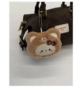 Close-up of a plush bear and cat bag charm on dark brown lychee leather handbag