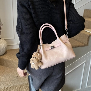 Detail view of pink PU leather tote with metal lock and cute plush puppy charm