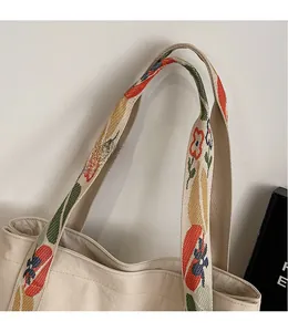Detail of the colorful floral pattern wide shoulder strap on a beige canvas tote bag