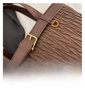 Detail of dark brown pleated texture with gold-tone hardware and leather strap